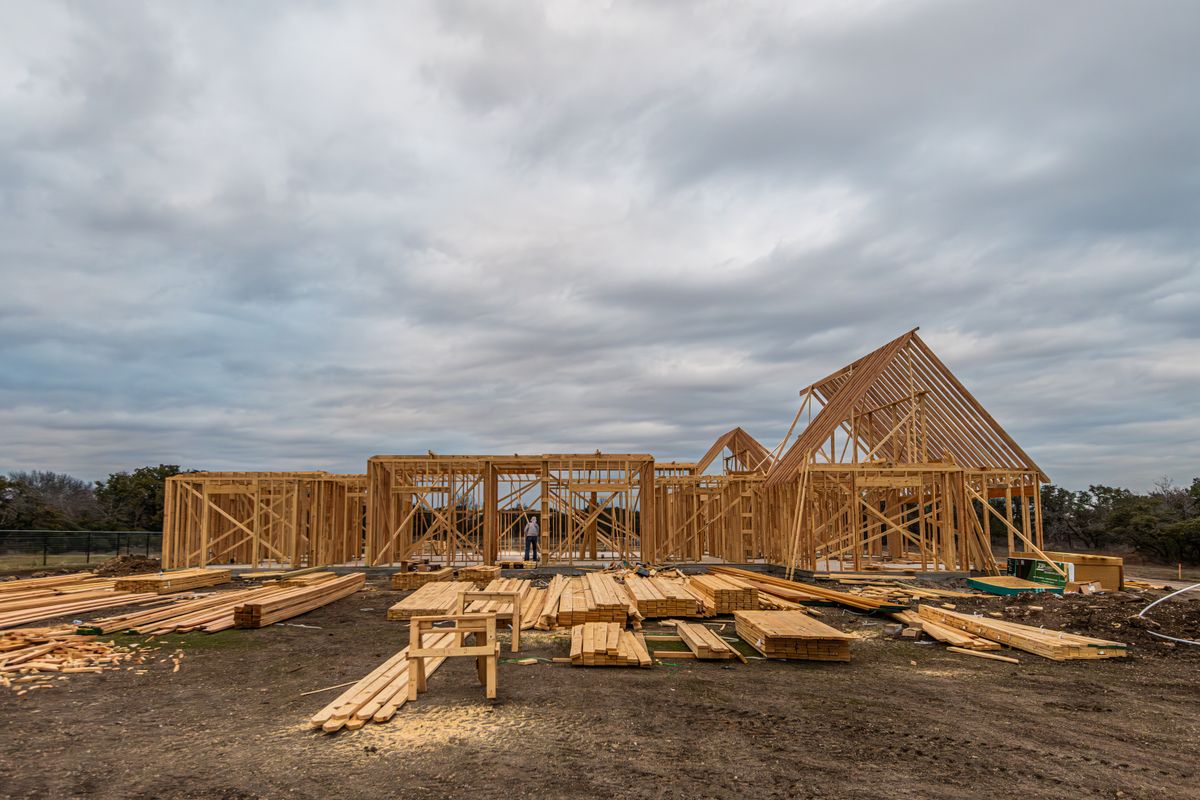 House framing under construction beneath a cloudy sky