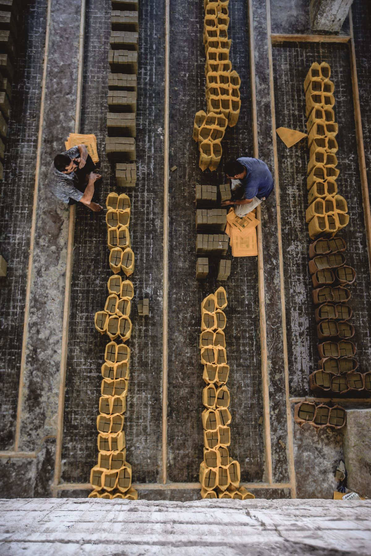 Overhead view of workers arranging paving bricks