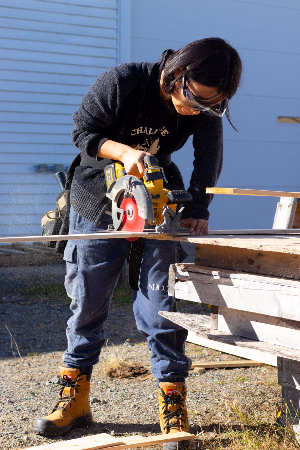 Carpenter wearing protective eyewear while cutting timber